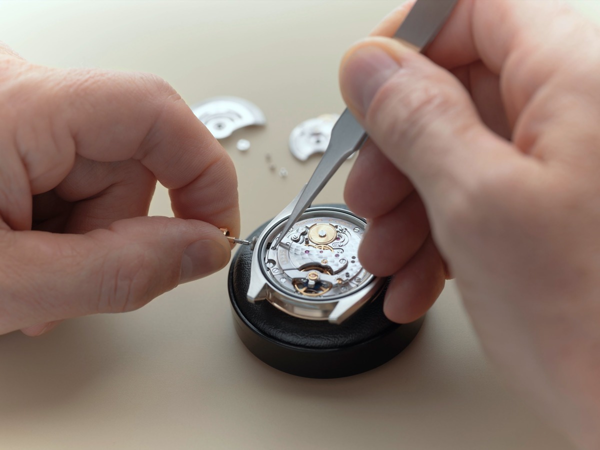 Uhrmacher bei der Revision eines Rolex Uhrwerks mit Pinzette